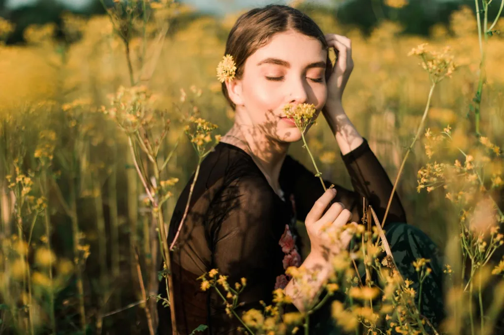 photo of woman smelling yellow flower